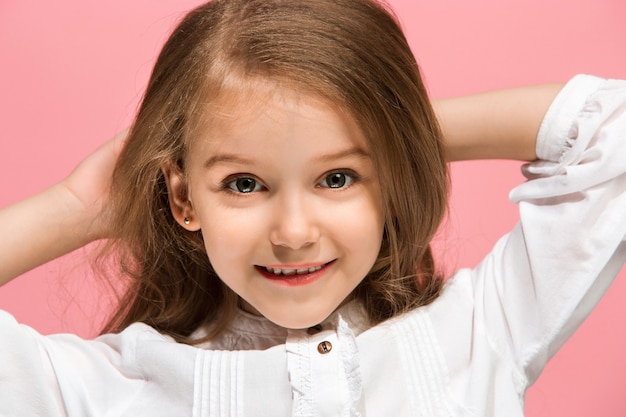 Feliz chica adolescente de pie, sonriendo aislado sobre fondo de estudio rosa de moda. Hermoso retrato femenino. Joven, satisfacer, niña