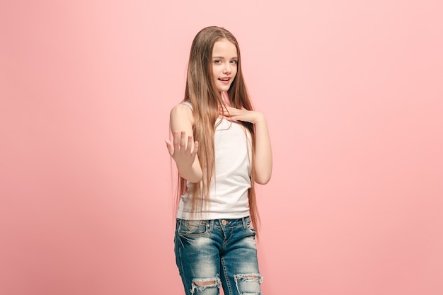 Feliz chica adolescente de pie, sonriendo aislado sobre fondo de estudio rosa de moda. Hermoso retrato femenino de medio cuerpo