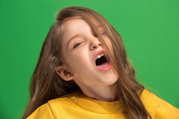 Feliz chica adolescente de pie, sonriendo aislado sobre fondo de estudio verde de moda. Hermoso retrato femenino. Joven, satisfacer, niña