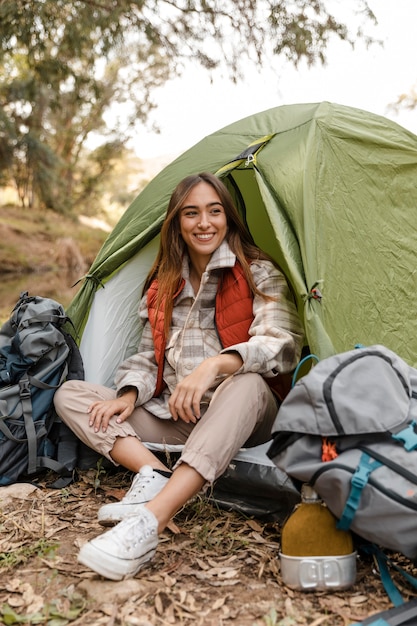 Feliz chica de camping en el bosque sentado en la tienda