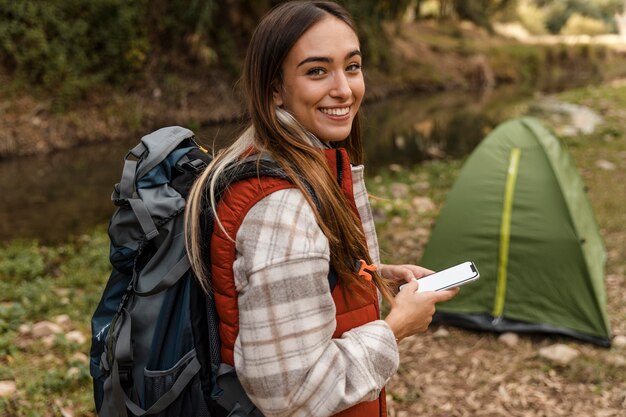 Feliz chica de camping en el bosque y tienda de campaña