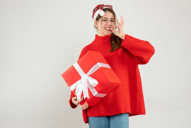 Feliz chica fiestera con gorro de Papá Noel con regalo en blanco