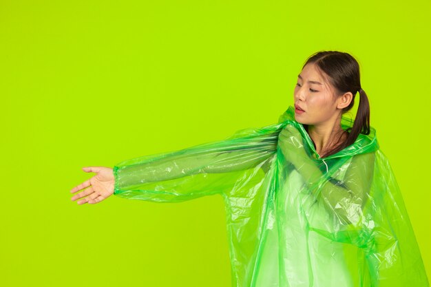 feliz chica hermosa, vistiendo ropa verde, paraguas y abrigo, día lluvioso.
