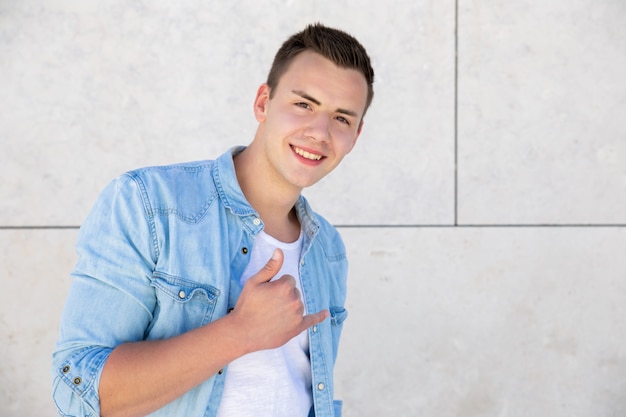 Feliz chico estudiante positivo haciendo llamarme signo