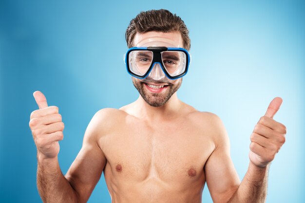 Feliz chico sonriente en gafas de natación mostrando pulgares arriba gesto