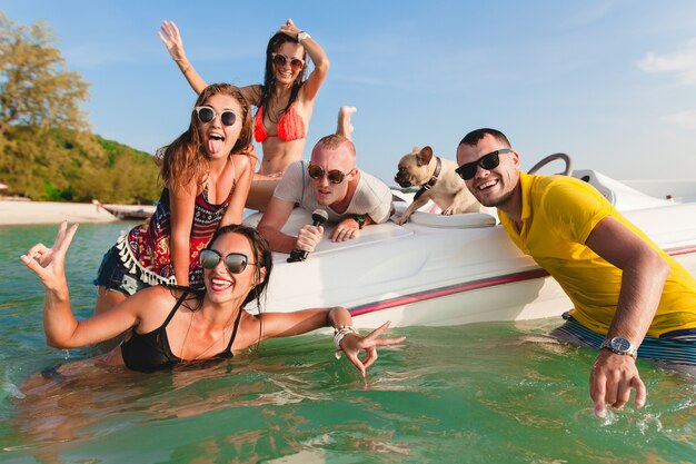Feliz compañía de amigos en vacaciones tropicales de verano en Tailandia viajando en barco en el mar, fiesta en la playa, gente divirtiéndose juntos, emociones positivas de hombres y mujeres