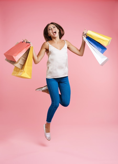 Feliz compra mujer saltando con un montón de bolsas de la compra