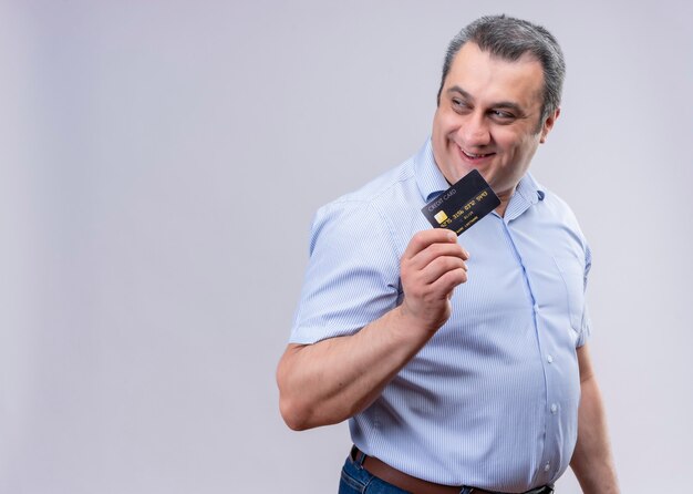 Feliz y contenido hombre de mediana edad vestido con camisa azul con tarjeta de crédito o un espacio en blanco