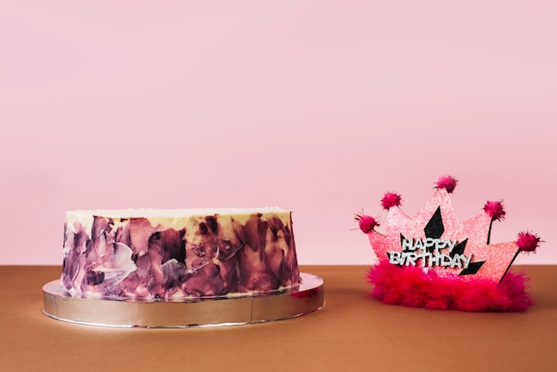 Feliz cumpleaños rosa corona con pastel circular contra fondo rosa