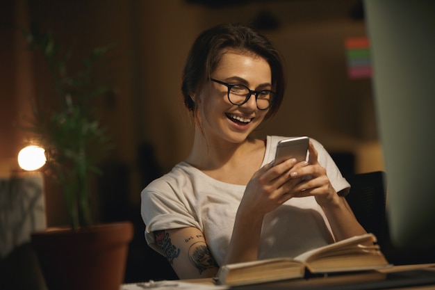 Feliz dama diseñadora sentada en el interior por la noche charlando