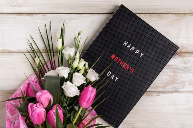 Feliz día del día de la madre a bordo junto a un ramo de flores.