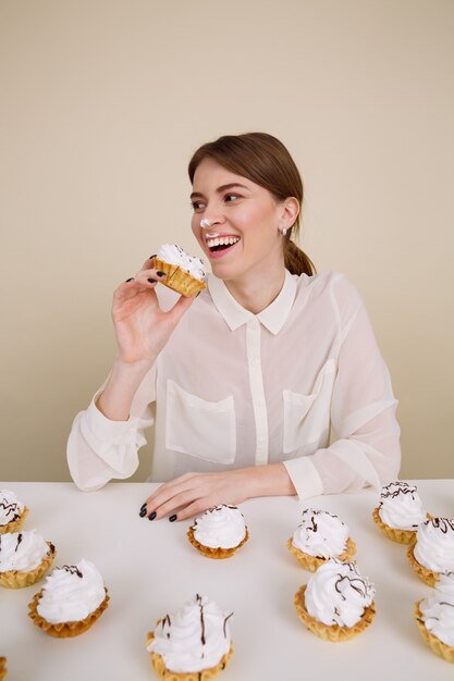 Feliz divertida joven sonriente y comiendo pasteles