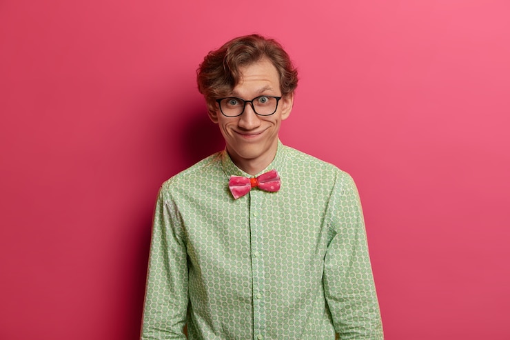 Foto gratuito feliz, divertido, inteligente, estudiante, se ve feliz, complacido de escuchar buenas palabras sobre el trabajo bien hecho, vestido formalmente, logra excelentes resultados en la ciencia, posa sobre una pared rosada brillante