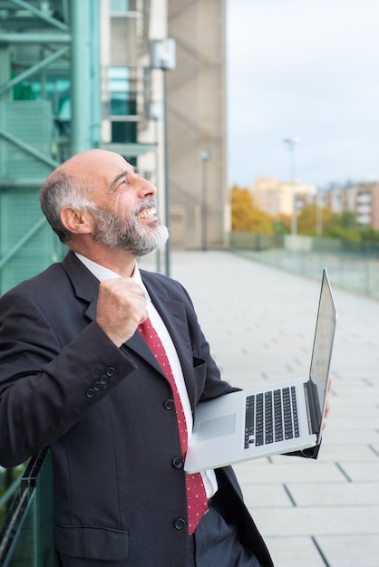 Feliz emocionado líder de negocios maduros con laptop