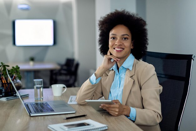 Feliz empresaria afroamericana trabajando en el panel táctil en la oficina