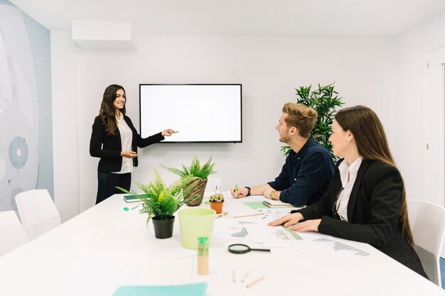 Feliz empresaria dando presentación a sus socios en reunión de negocios