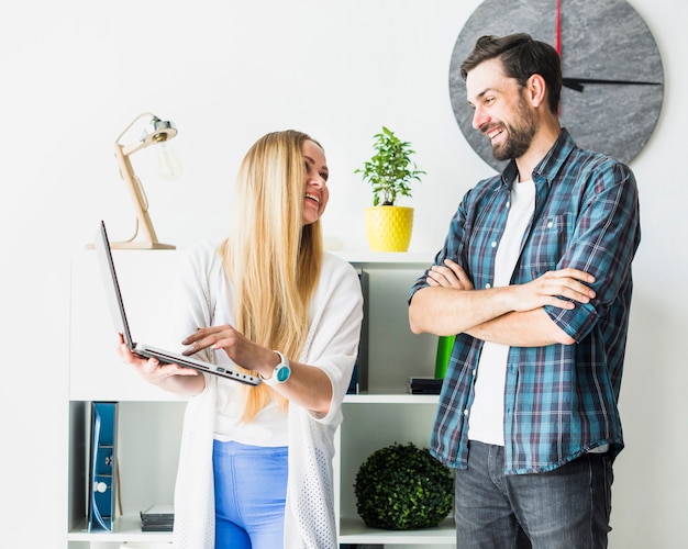 Feliz empresaria mostrando portátil a su colega