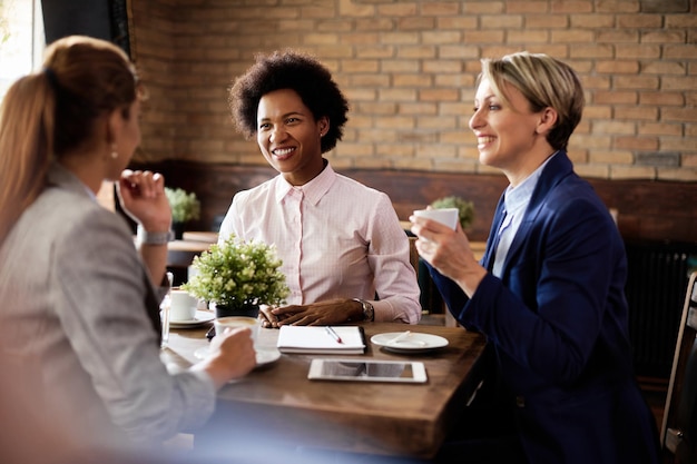 Feliz empresaria negra hablando con sus colegas en un café