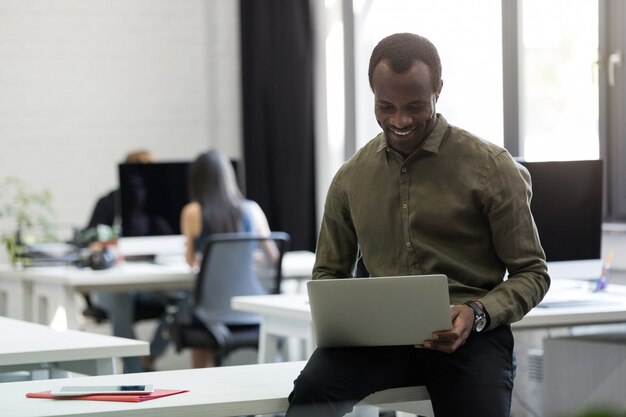 Feliz empresario afroamericano sentado en su escritorio y escribiendo