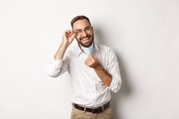 Feliz empresario quitarse la mascarilla y sonriendo, de pie