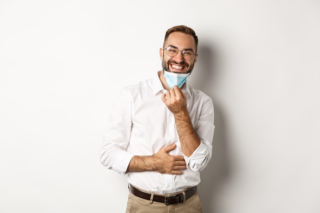 Foto gratuita feliz empresario quitarse la mascarilla y sonriendo, de pie