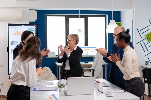 Feliz equipo diverso emocionado del equipo financiero en la sala de conferencias después de una estrategia exitosa