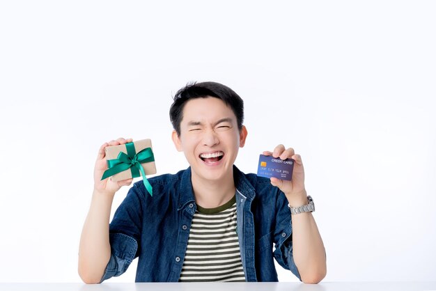 Feliz estilo de vida casual masculino asiático sonrisa reír mano sostener tarjeta de crédito y caja presente salir hombre asiático con gran éxito promoción concepto de ideas de negocios