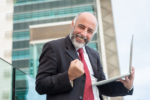 Feliz exitoso líder de negocios maduros con laptop