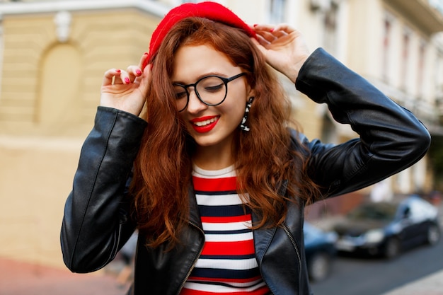 Feliz fabulosa mujer de jengibre en elegante boina roja en la calle