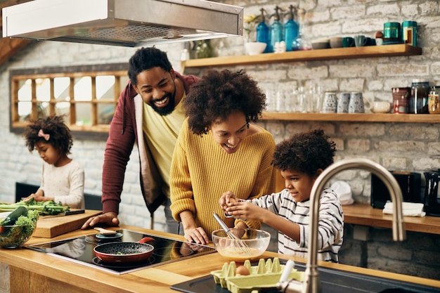 Feliz familia afroamericana disfrutando mientras prepara la comida juntos en la cocina