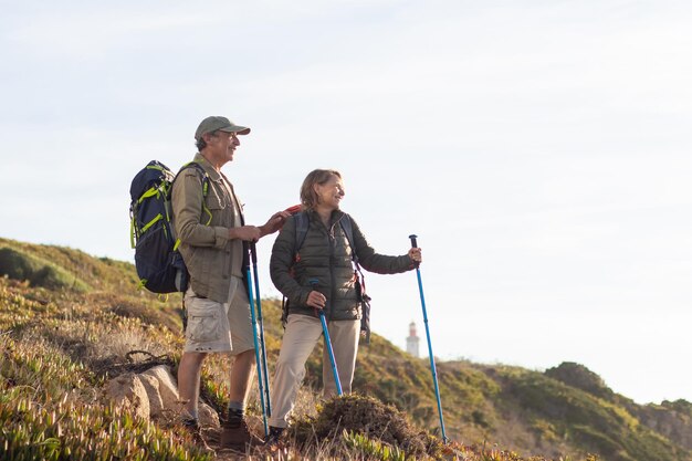 Feliz familia de ancianos haciendo senderismo en verano. Hombre y mujer con ropa informal y con municiones mirando el paisaje. Hobby, concepto de estilo de vida activo