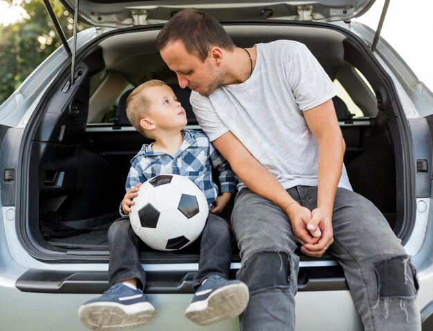 Feliz familia monoparental sentada en la parte trasera del coche