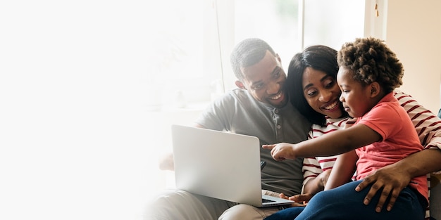 Feliz familia negra y un niño pequeño apuntando a un espacio de diseño de pantalla de computadora portátil