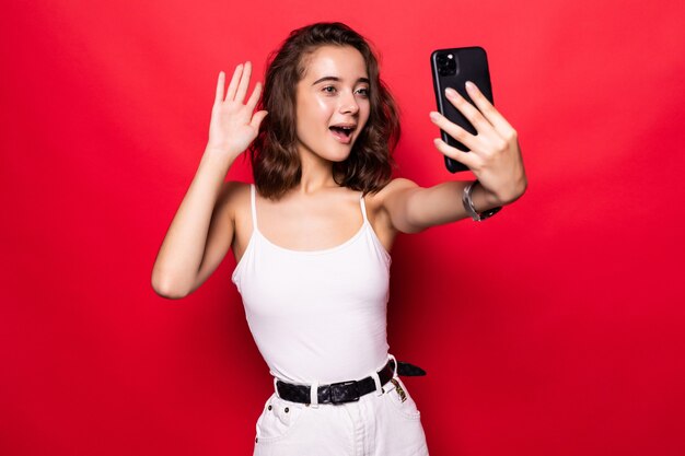 Feliz foto de mujer tomando selfie y agitando la mano en su teléfono inteligente