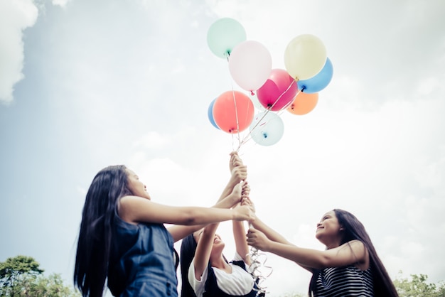 Feliz grupo de amigas mano sosteniendo globos multicolores