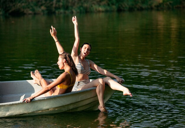 Feliz grupo de amigos divirtiéndose mientras se ríe, salpica agua y nada en el río