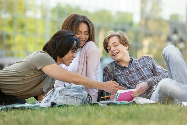 Feliz grupo de estudiantes multiétnicos que estudian al aire libre