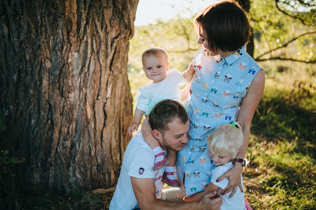 Foto gratuita feliz hermosa familia en el gran jardín en el tiempo del amanecer