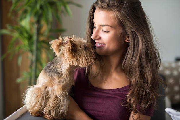 Feliz hermosa joven posando con su perro pequeño