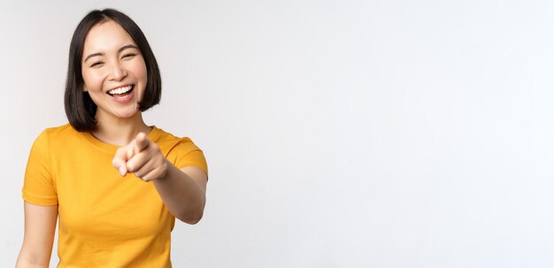 Feliz hermosa mujer asiática riendo señalando con el dedo a la cámara y riéndose sonriendo despreocupada de pie