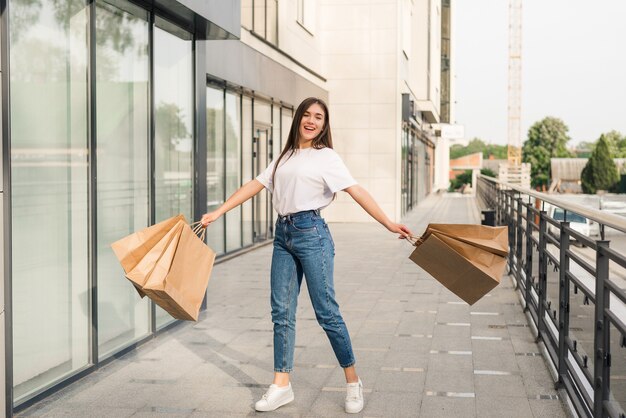 Feliz hermosa mujer con bolsas de colores en la mano saltando alegremente en el aire.