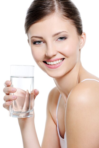 Feliz hermosa mujer con dientes blancos sanos sosteniendo el vaso de agua limpia