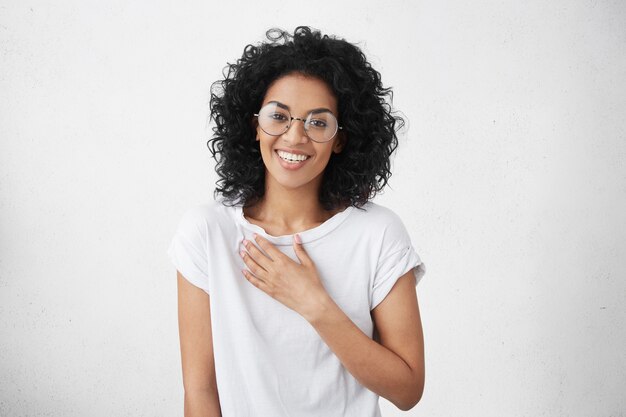 Feliz hermosa mujer joven de piel oscura de buen corazón con grandes gafas redondas