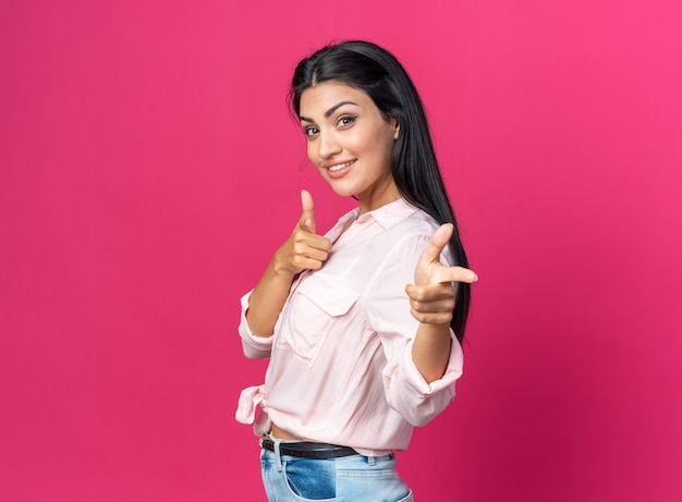 Feliz hermosa mujer joven en ropa casual sonriendo confiado apuntando con los dedos en la parte delantera