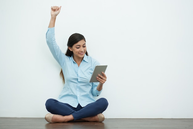 Feliz hermosa mujer joven en suelo con la tableta