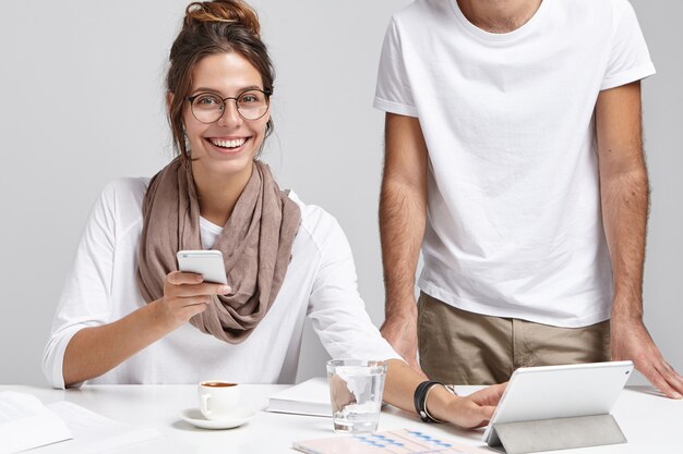 Feliz hermosa mujer usa teléfonos inteligentes y tabletas estando siempre en contacto