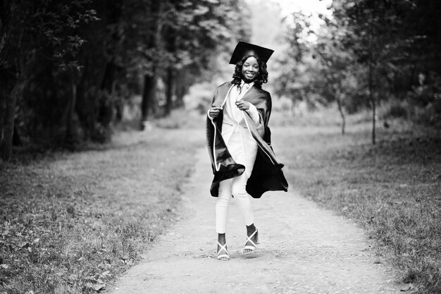 Feliz hermosa niña afroamericana negra con sombrero y vestido graduados