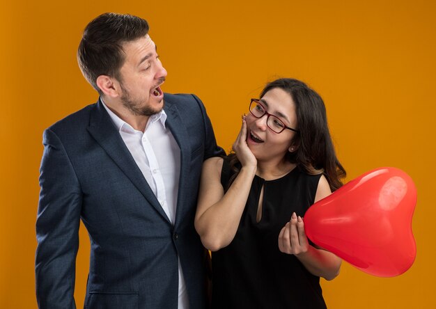 Feliz y hermosa pareja hombre y mujer con globo rojo en forma de corazón divirtiéndose celebrando el día de san valentín