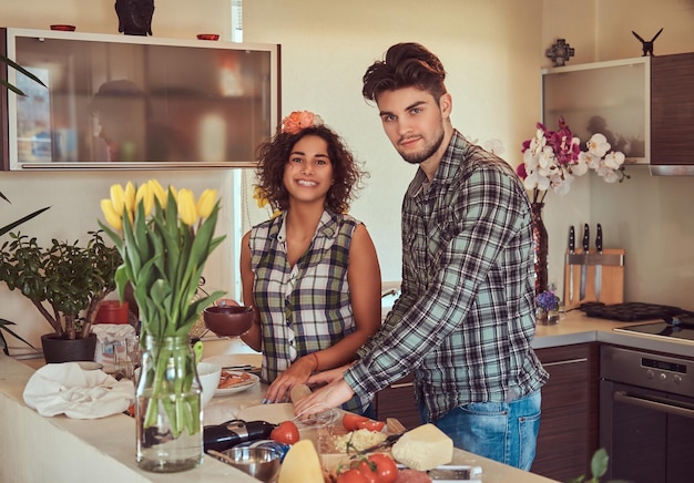 Feliz hermosa pareja joven cocinando en la cocina en casa.