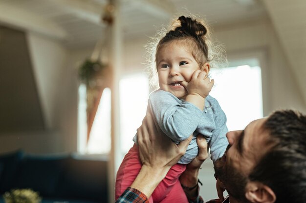 Feliz hija pequeña y su padre divirtiéndose mientras pasan tiempo juntos en casa